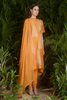 a woman in a orange dress standing in a garden 